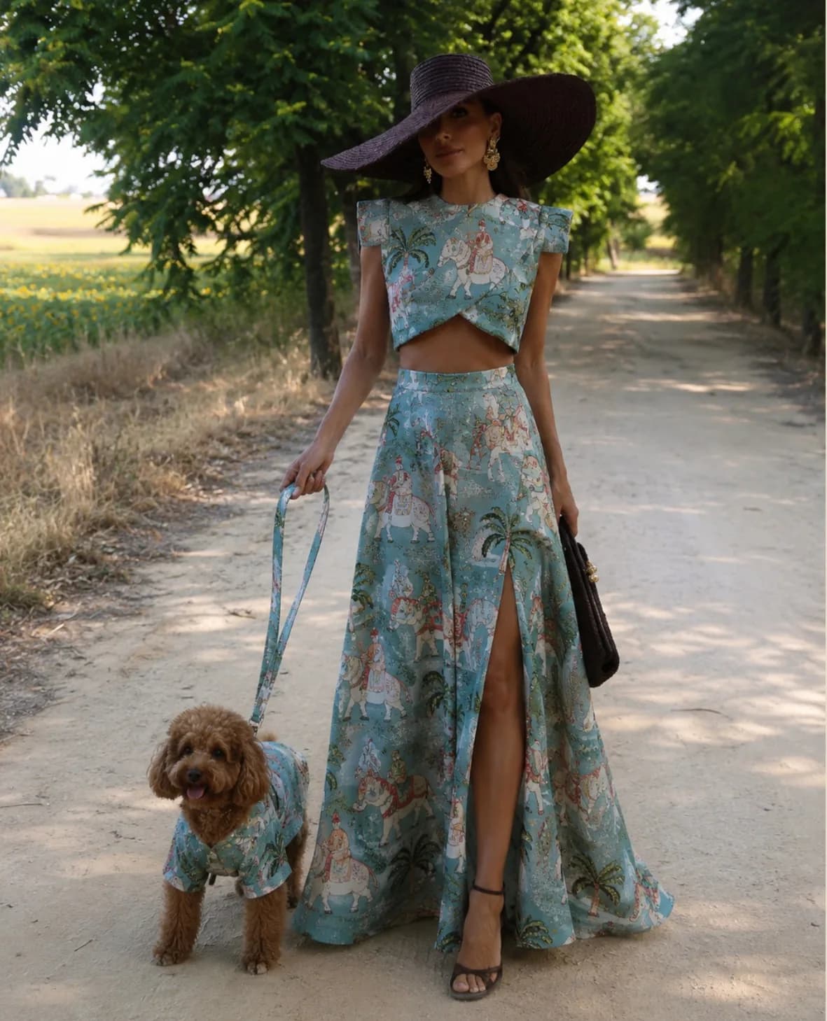 Editorial de la colección Animal Care: modelo con vestido de estampado de elefantes paseando a su perro, que lleva el mismo estampado, junto al mueble Oddie coral