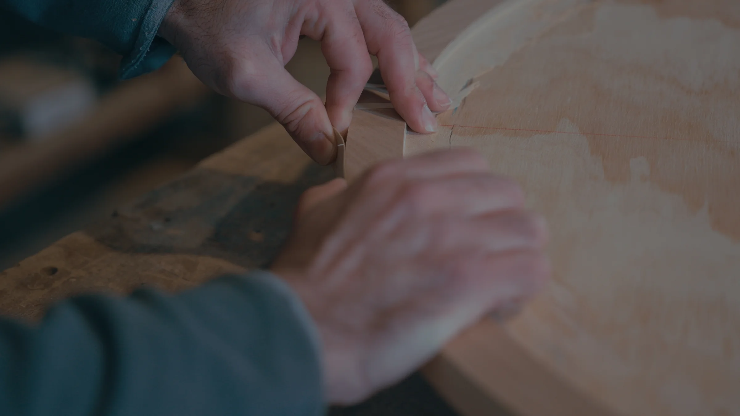Hands finishing the edge of a wooden piece